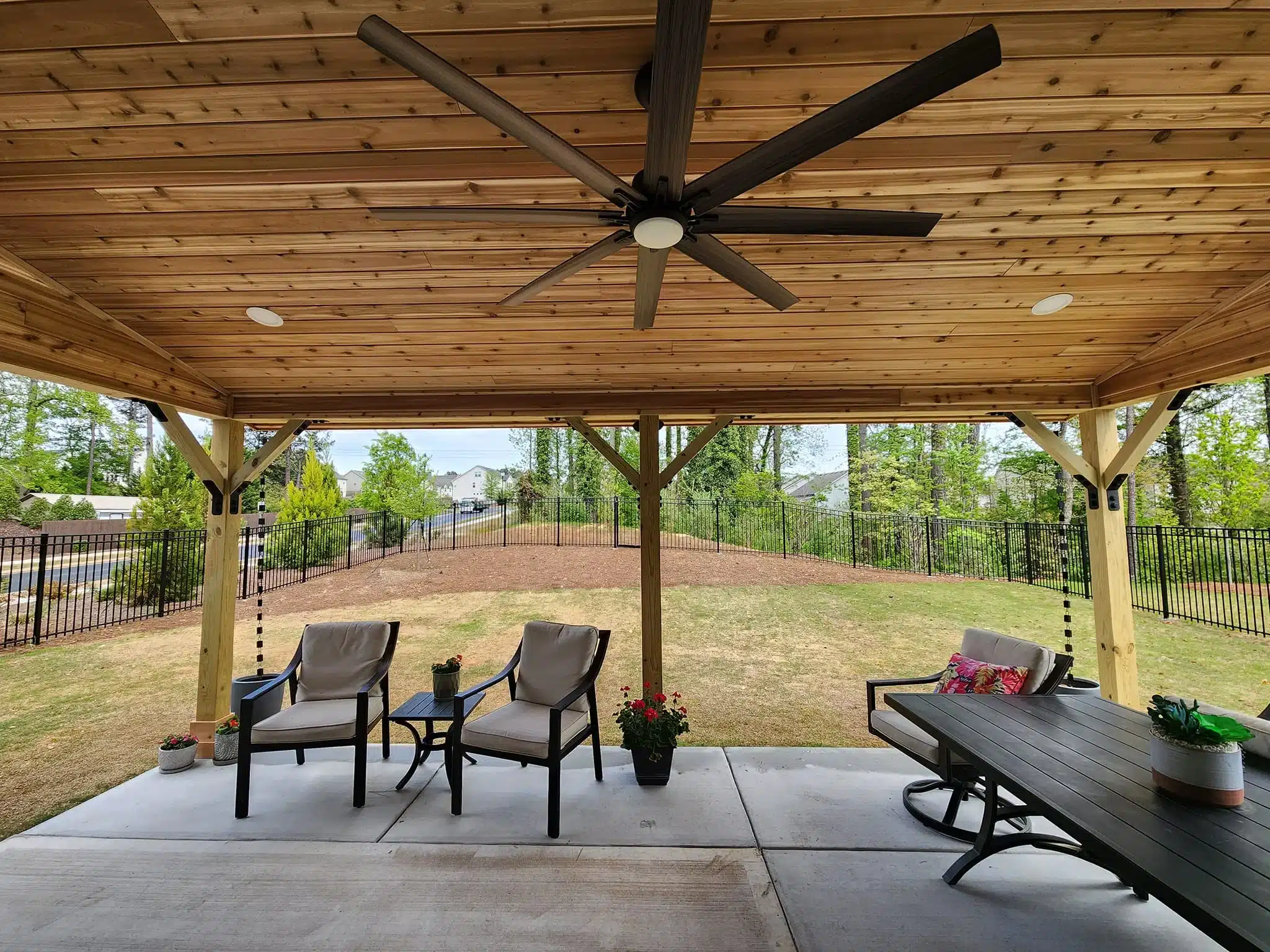Outdoor covered patio with wood ceiling, large fan, and outdoor seating area.
